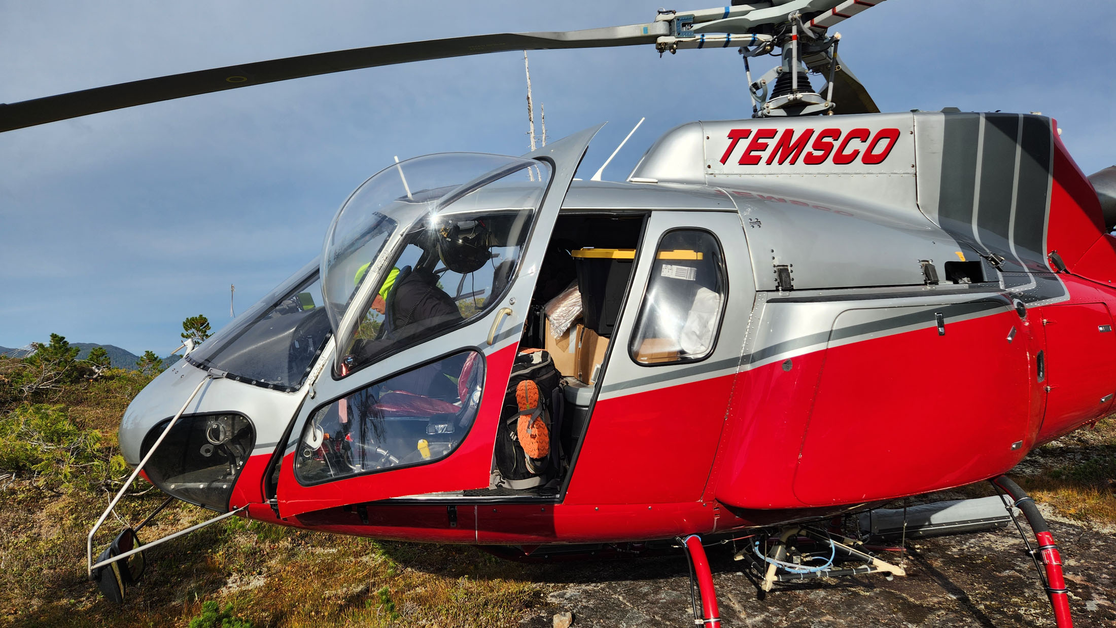 Red helicopter parked in a natural environment.
