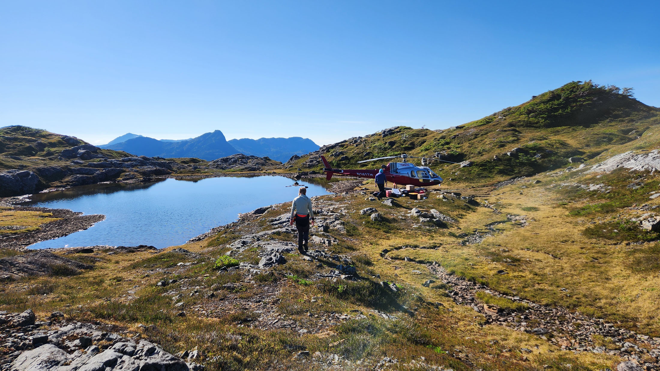 Person walking near a helicopter by a lake